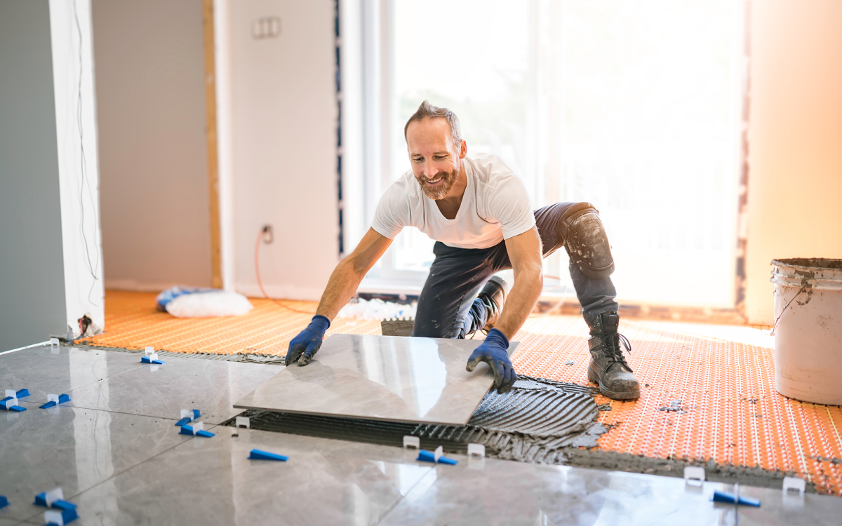 Worker installing tile floor in home restoration project